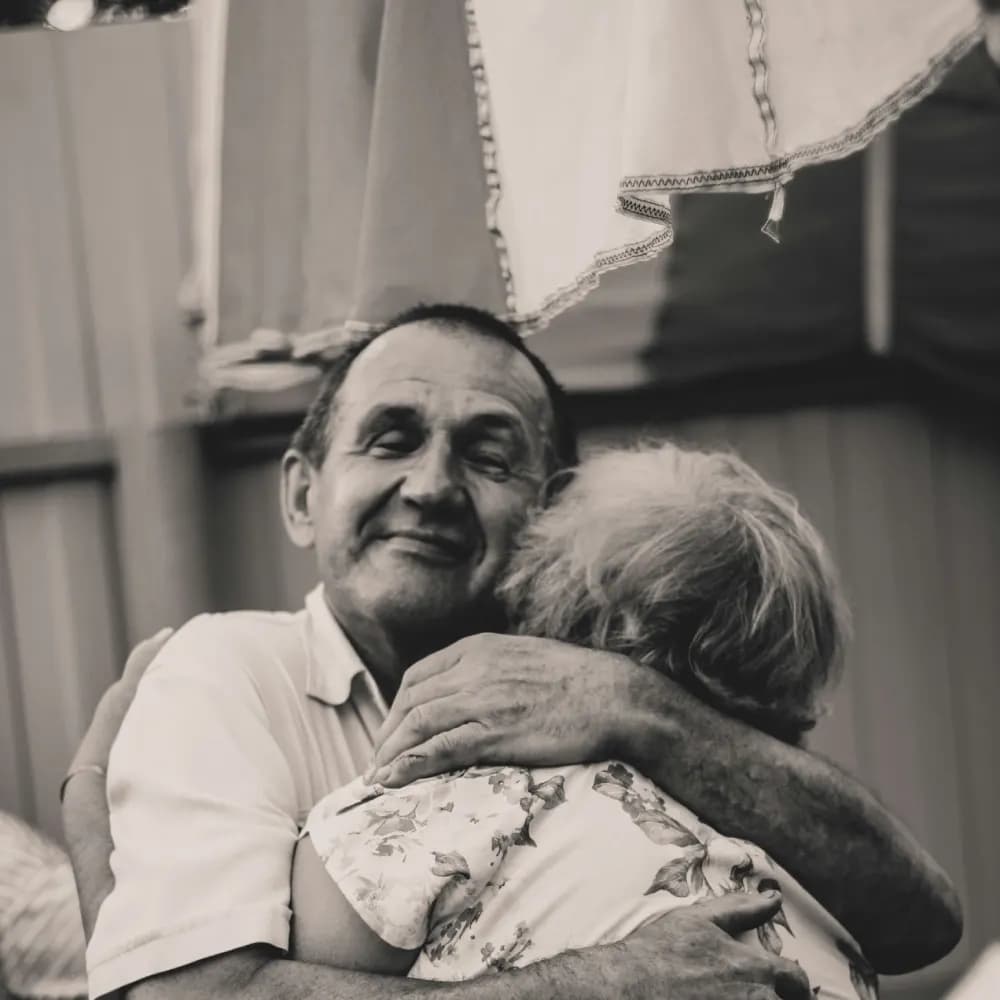 Un bărbat care îmbrățișează o femeie vârstnică, fotografie alb-negru